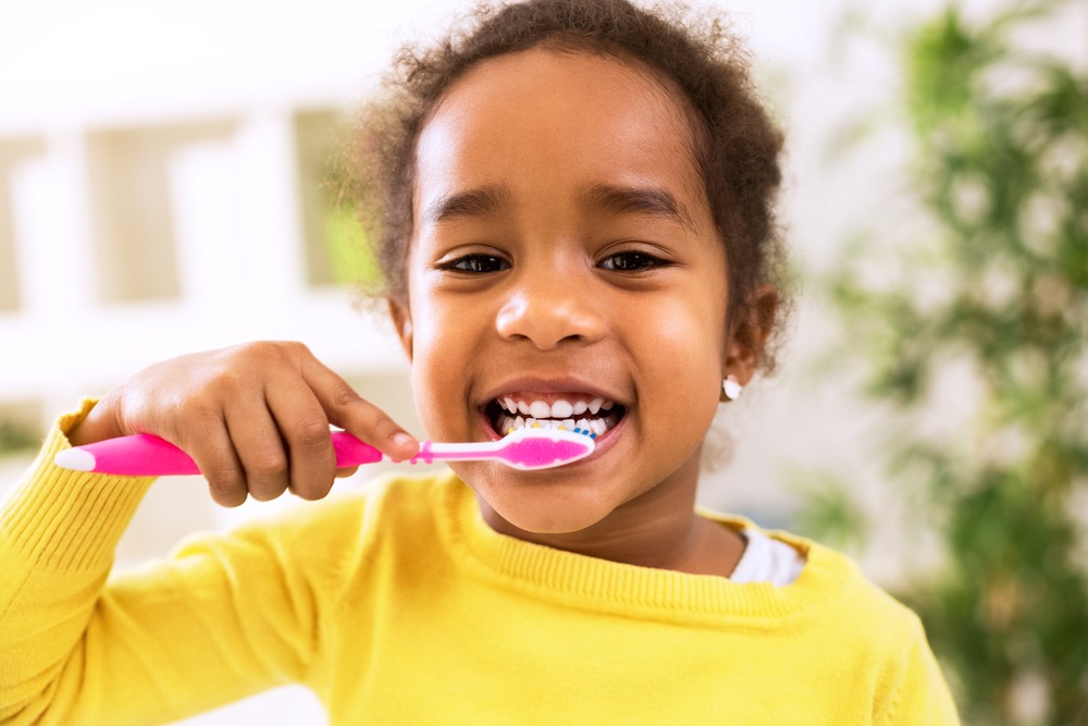 child brushing her teeth with a smile